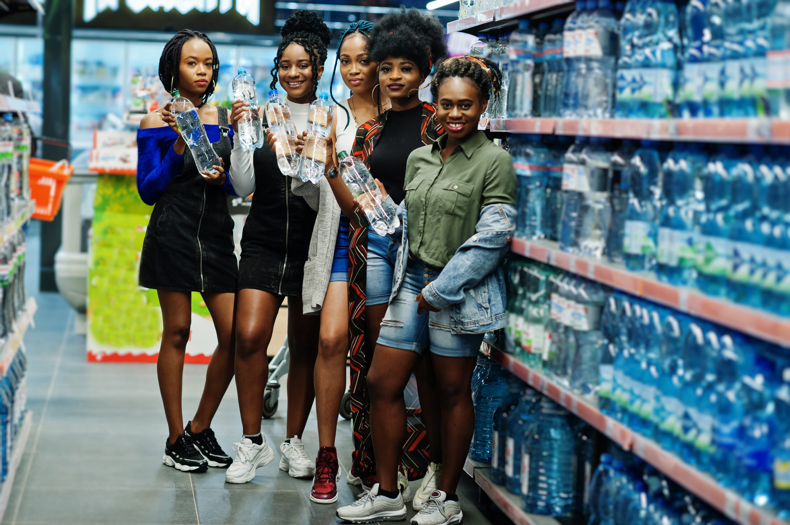 Group of five african womans with plastic bottles of water in supermarket.